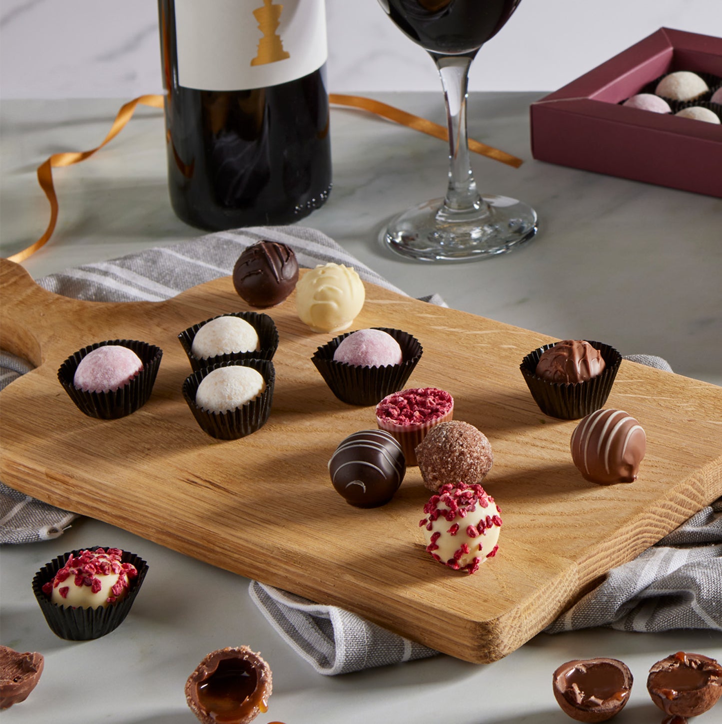 Luxury assorted milk, dark and white chocolate truffles on a wooden board served with wine